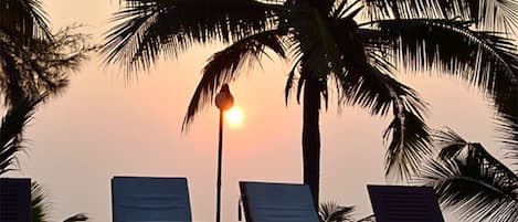 Una piscina al aire libre, sombrillas, sillones reclinables de piscina