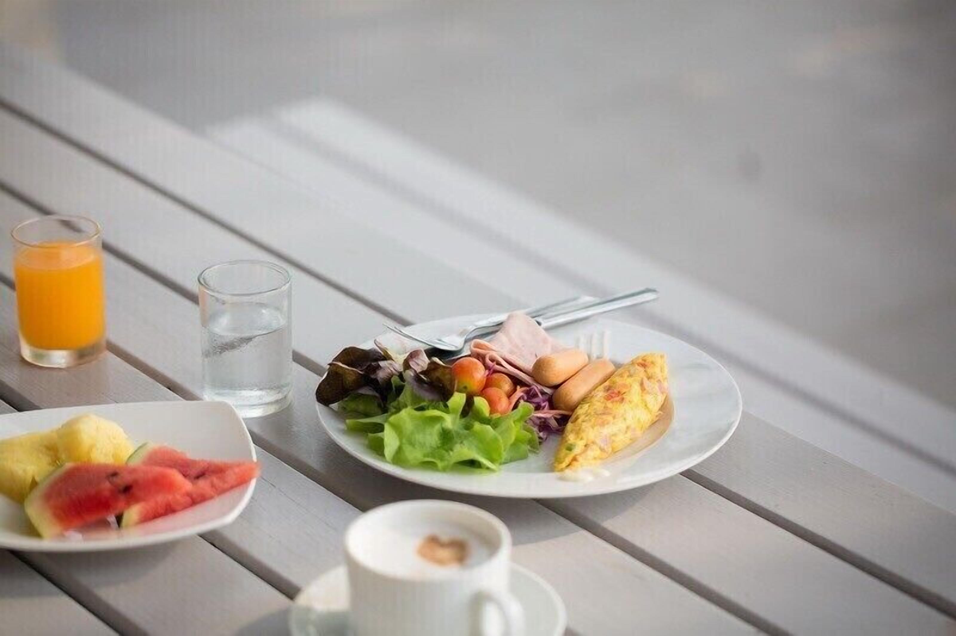 A breakfast setting with plates of food, a glass of orange juice, a glass of water, and a cup of coffee on a wooden table.