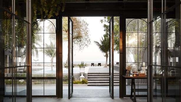 A modern hotel entrance with large glass doors leading to a pool area. - SiamBeach Resort (Cha-am)