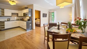 A modern kitchen with white cabinets and a dining area with wooden furniture. - SKY Apartments VisitZakopane (Zakopane)