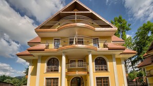 A large, yellow building with a symmetrical facade, multiple balconies, and a central entrance with a large arched doorway. - SKY Apartments VisitZakopane (Zakopane)