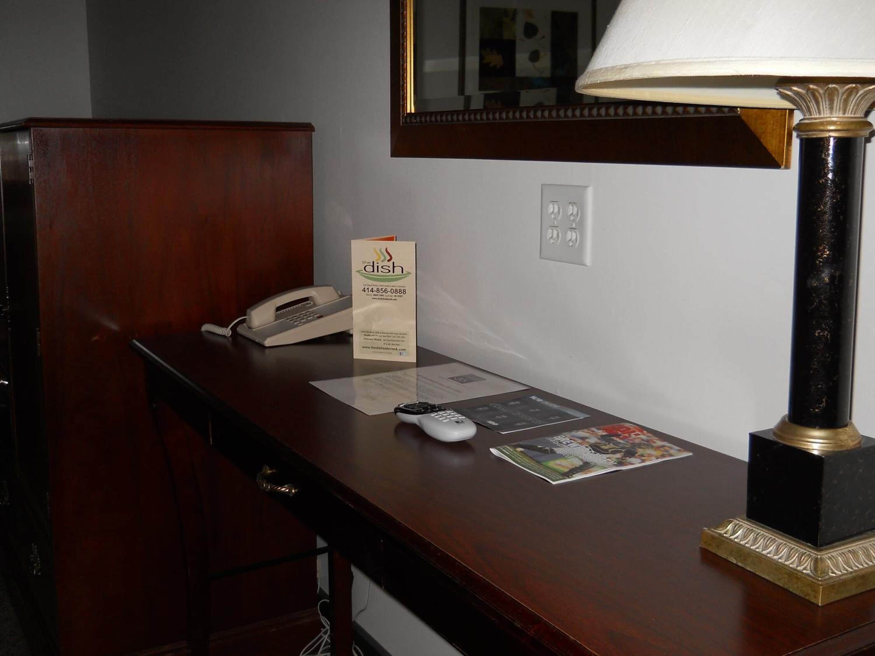 A hotel reception desk with a telephone, a lamp, a menu, and a magazine.