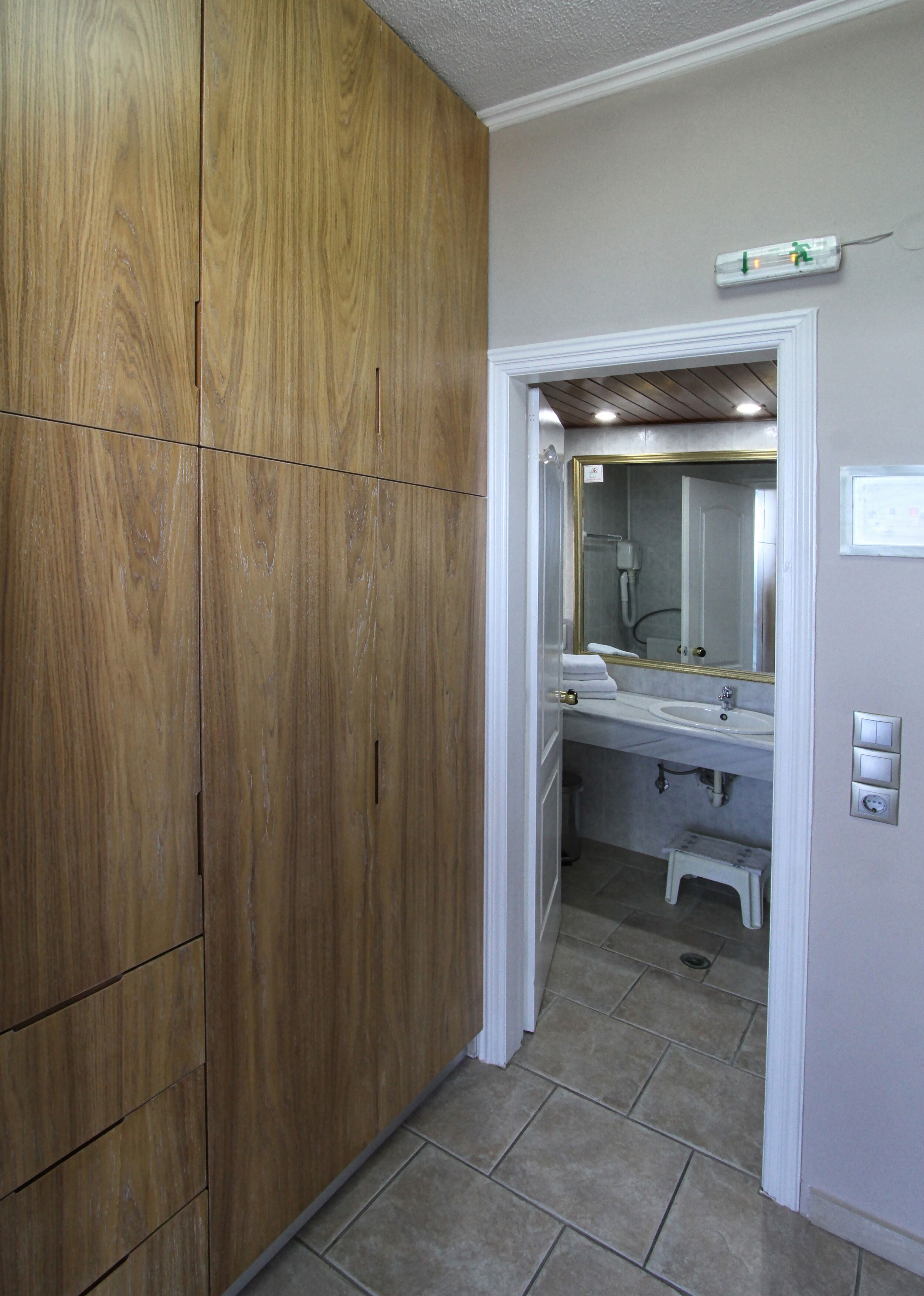 Un baño con un armario de madera, un lavamanos y un espejo.