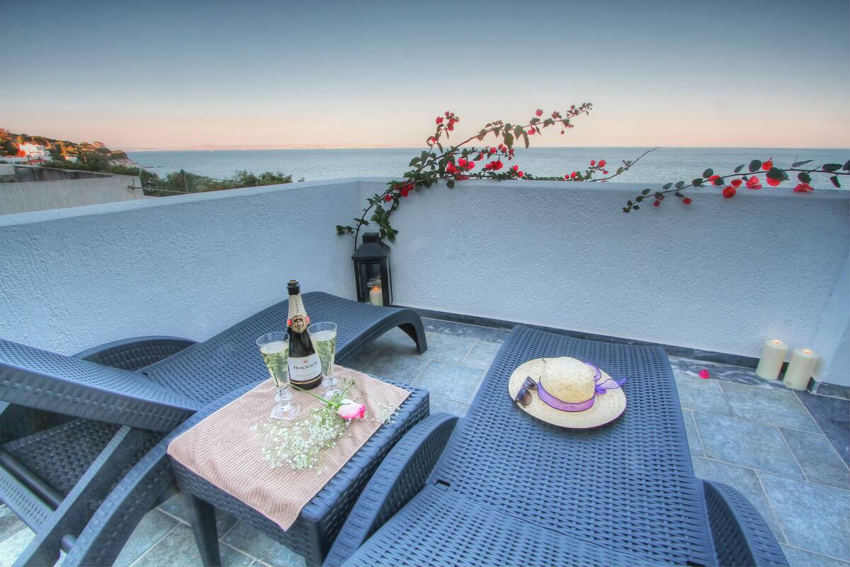 Una terraza con una mesa preparada para dos, con vista al mar.