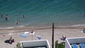 A beach with clear water, sun loungers, umbrellas, and a flag. - Chios Xenia Studio & Apartments (Chios)