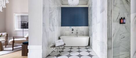 A modern bathroom with a bathtub, a round mirror, and a towel rack.