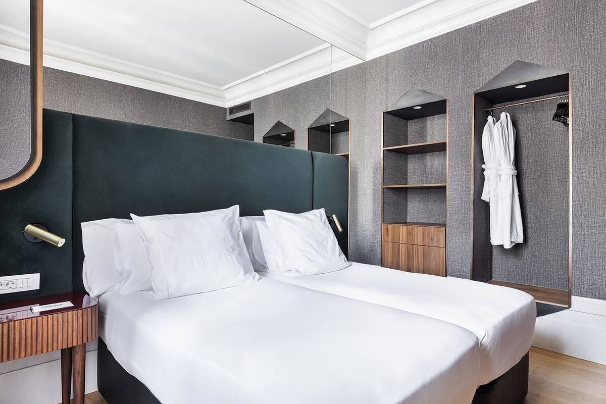 Een moderne hotelkamer met een groot bed, een garderobe en een ingebouwde kledingroede.