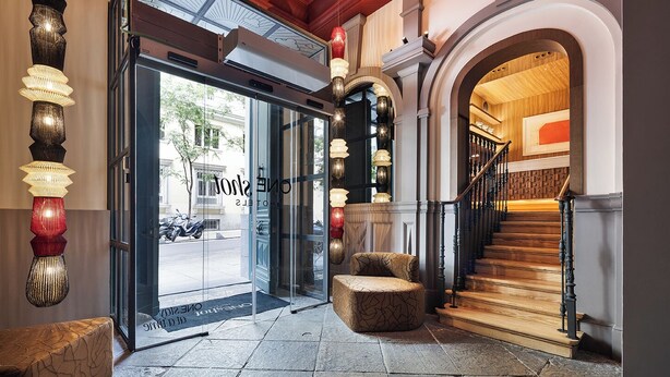 A hotel entrance with a glass door, a staircase, and decorative lighting. - One Shot Recoletos (Madrid)