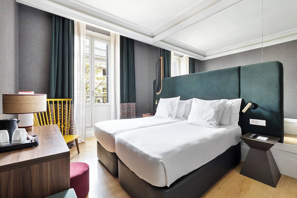 Hotelkamer met een groot bed, nachtkastjes, een bureau met lamp en uitzicht.