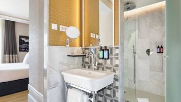 A modern bathroom with a glass shower enclosure, a white sink, and a mirror.