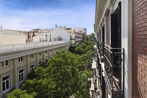 Un edificio de varios pisos con balcones y una fila de árboles en primer plano.