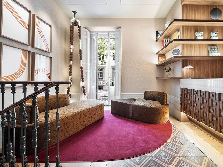Een modern interieur met een trap, een rode loper en een houten boekenkast.