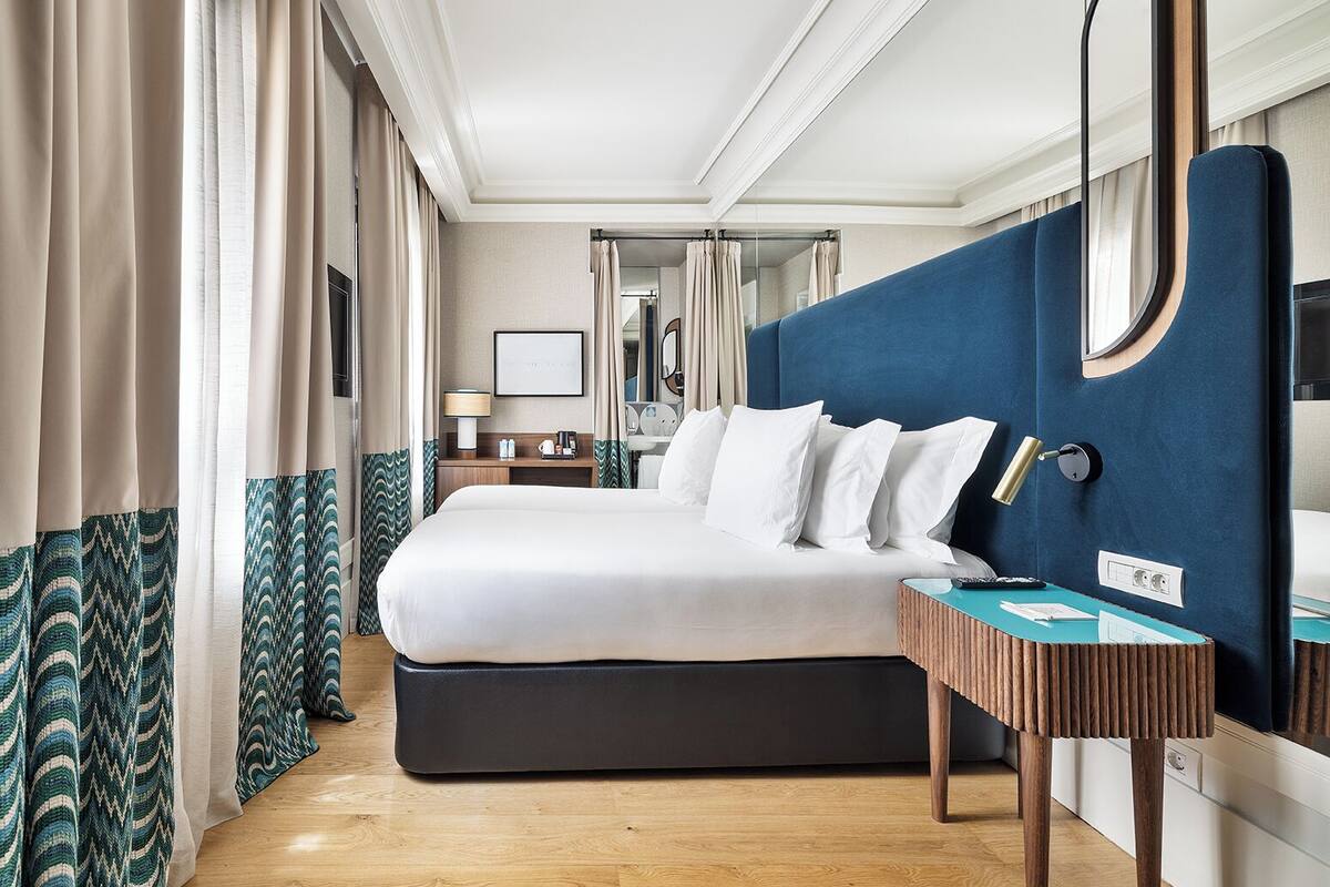 Een moderne hotelkamer met een groot bed, een nachtkastje, een spiegel en uitzicht op de badkamer.