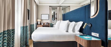 Une chambre d’hôtel moderne avec un grand lit, une table de chevet, un miroir et une vue sur la salle de bain.