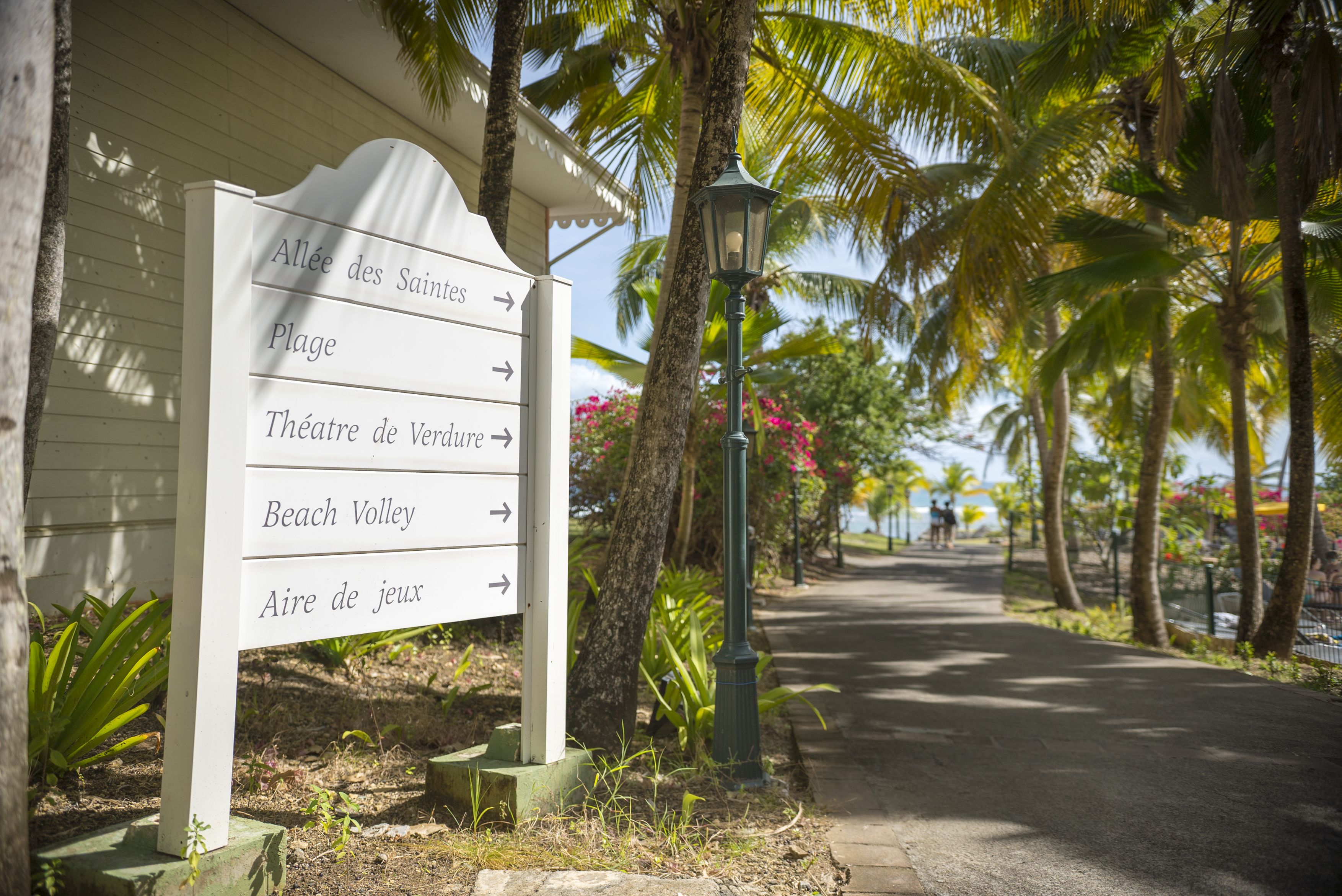 A sign with directions to various locations including 'Allée des Saintes', 'Plage', 'Théâtre de Verdure', 'Beach Valley', and 'Aire de jeux'.