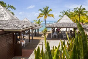 A beachside restaurant with outdoor seating and a view of the ocean.