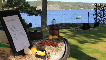 A seafood platter with a menu on a table by a lake.