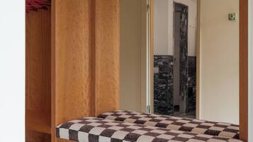 Un dormitorio con un armario de madera, un colchón a cuadros y un espejo.