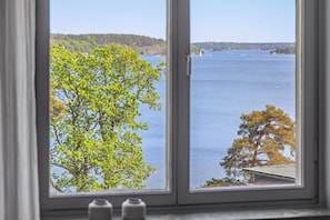 A window view of a lake with trees and a distant shoreline. - Vår Gård Saltsjöbaden (Saltsjobaden)
