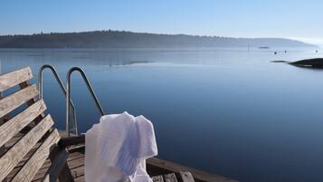 Une jetée en bois, dotée de rampes métalliques et sur laquelle est posée une serviette blanche sur un banc.