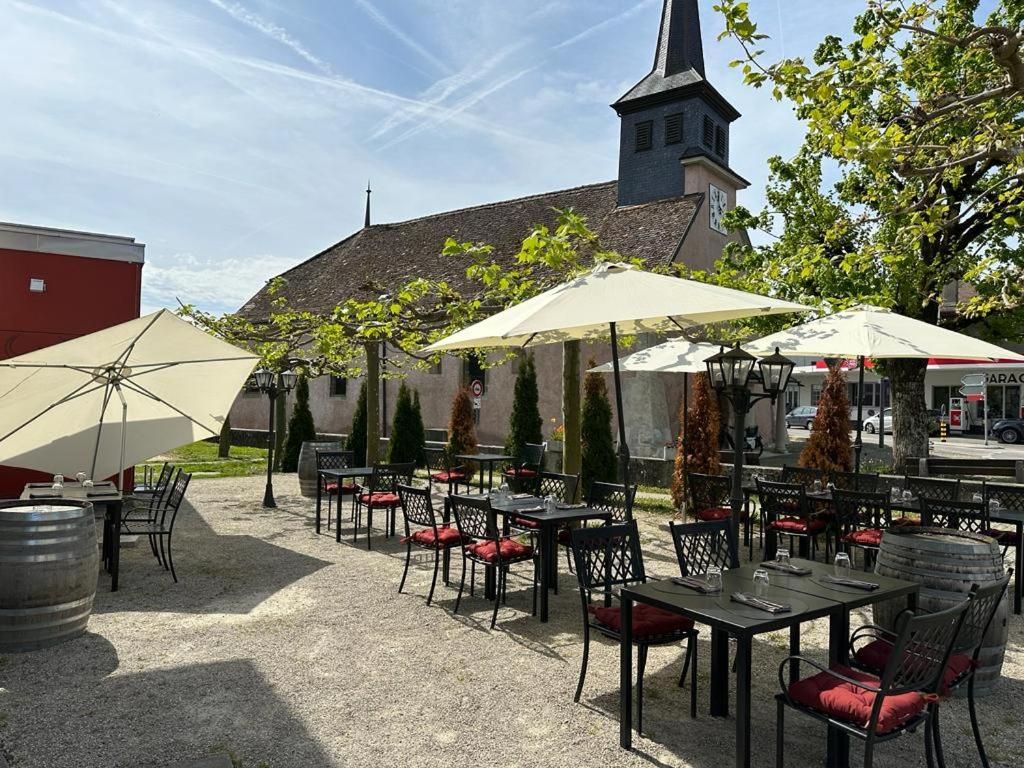 Un café en plein air avec des tables et des chaises, des parasols, et une église en arrière-plan.
