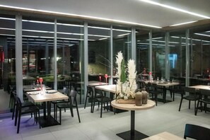 A modern restaurant interior with glass walls, multiple dining tables, and chairs. - Hôtel au Boeuf Rouge (Crassier)