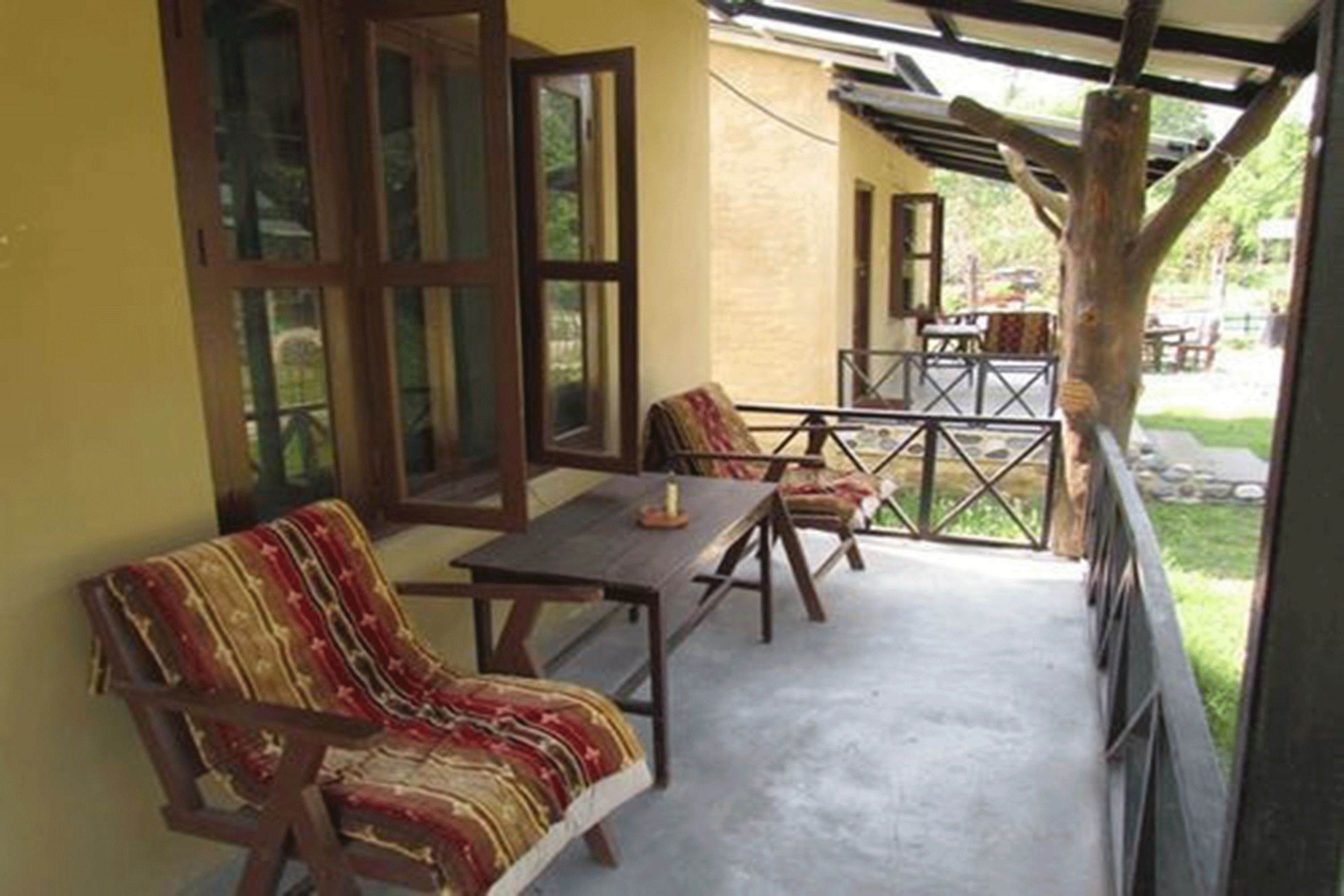 A covered outdoor seating area with wooden furniture and a view of the garden.