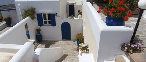A white-washed building with blue accents, stone steps, and potted flowers.