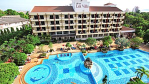 Un hôtel à plusieurs étages, doté d’une piscine et entouré de verdure.