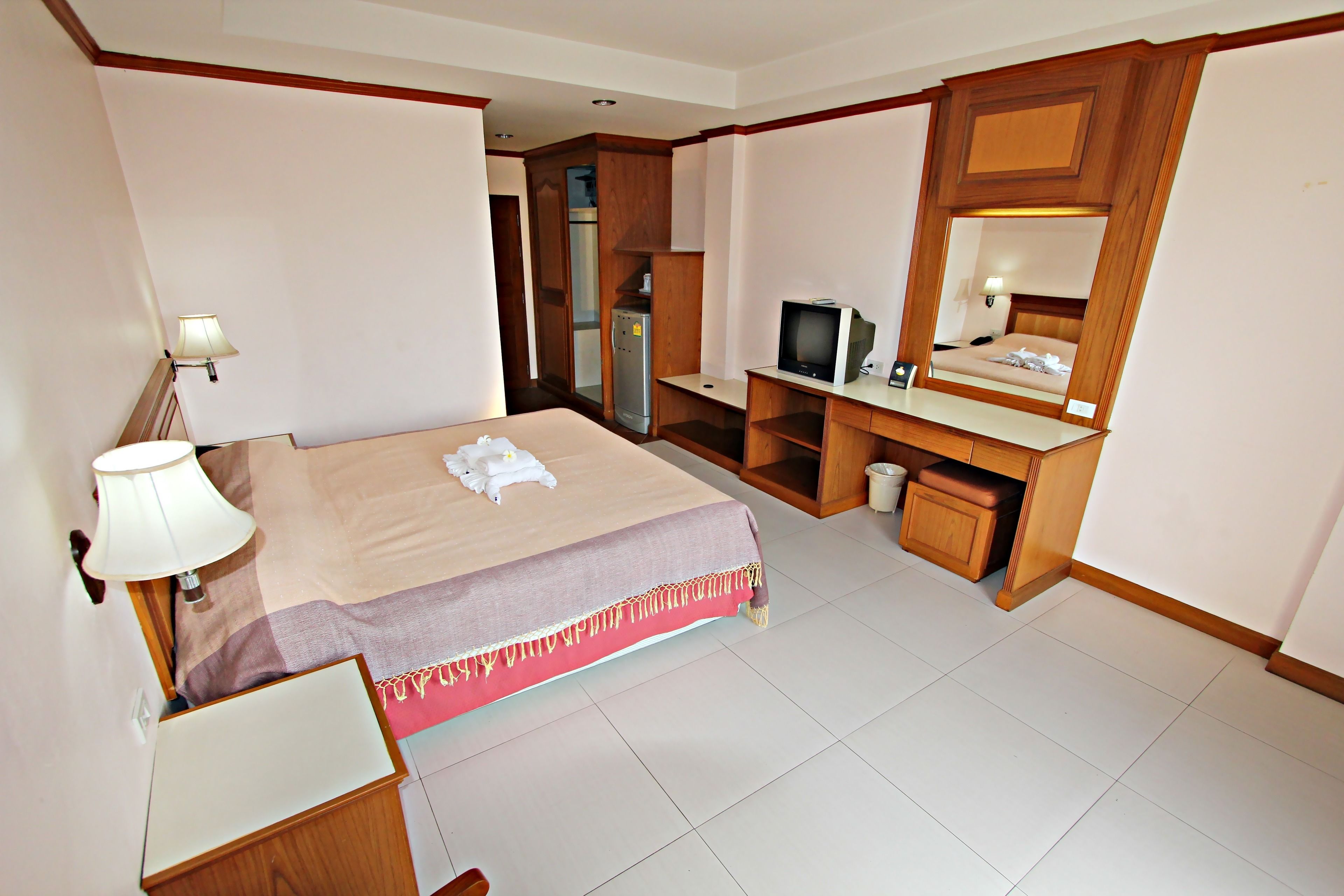 A hotel room with a bed, a desk, a television, and a mirror.