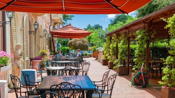 An outdoor patio with tables and chairs, a statue, and a pergola covered with greenery. - Grand Hotel du Park et Regina (Montecatini Terme)