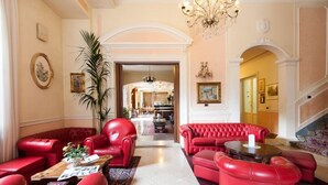 A spacious lobby with red leather sofas, a chandelier, and a grand staircase. - Grand Hotel du Park et Regina (Montecatini Terme)