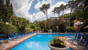 A swimming pool with blue water, surrounded by lounge chairs and potted plants. - Grand Hotel du Park et Regina (Montecatini Terme)