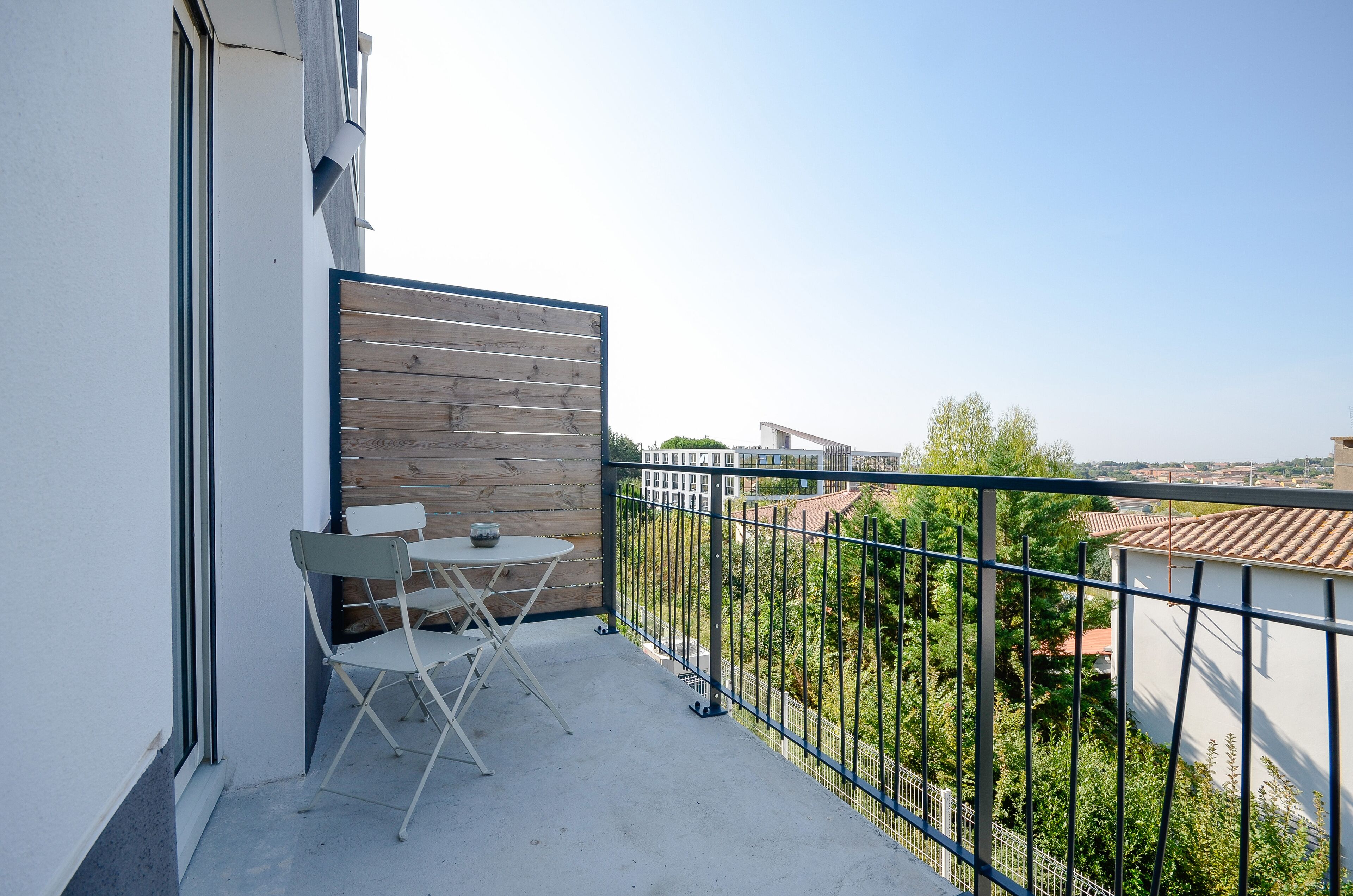 A balcony with a wooden panel wall, a metal railing, and a view of a cityscape.