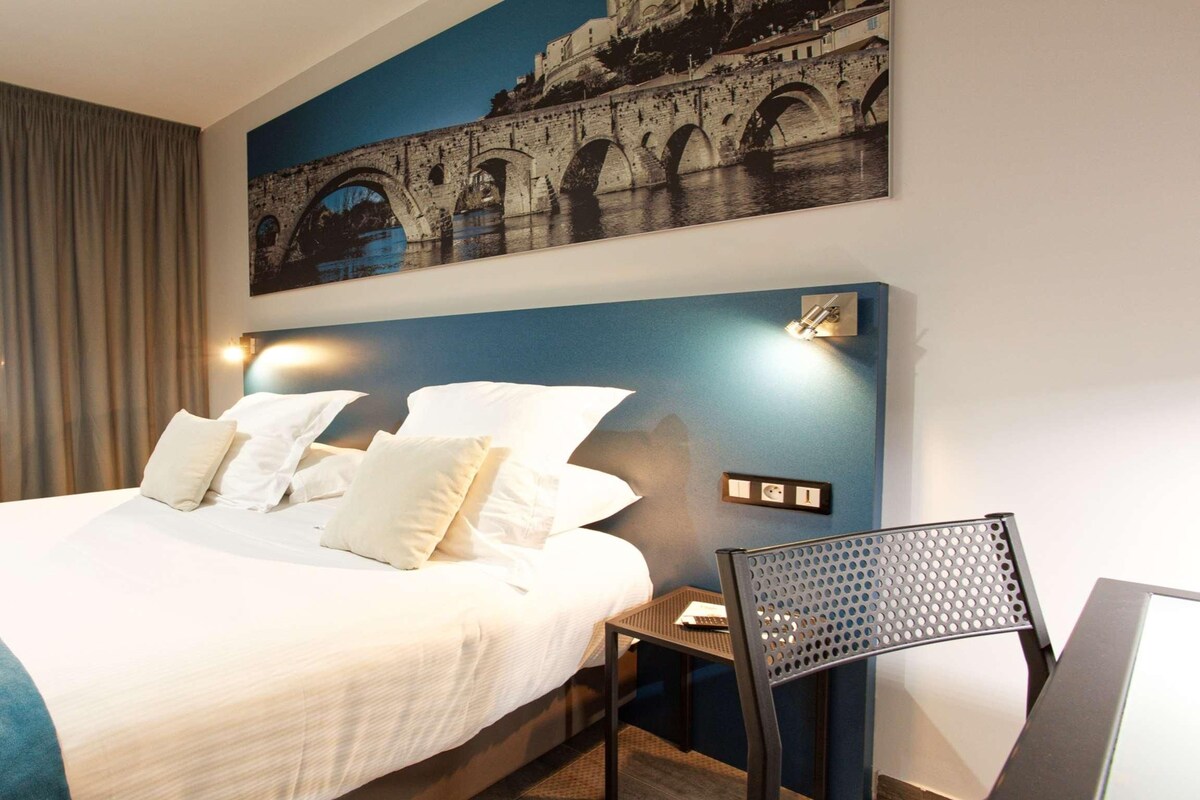 Une chambre d’hôtel avec un grand lit, une tête de lit dotée de lampes murales, une table de chevet et une chaise.