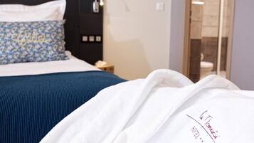 A hotel room with a bed, a nightstand, a robe, and a bathroom visible through an open door.