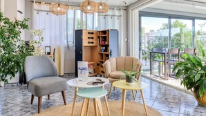 A modern living room with a grey armchair, a beige armchair, a small round table, and a bookshelf.