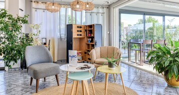 Una sala de estar moderna con un sillón gris, un sillón beige, una mesita redonda y una estantería.