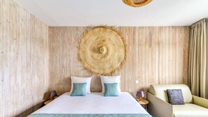 A hotel room with a bed, two pillows, a chair, a bedside table, and a woven wall hanging. - Sure Hotel by Best Western Beziers Le Monestie (Boujan-sur-Libron)