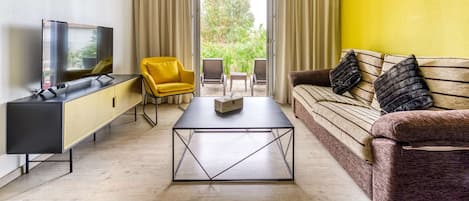 A modern living room with a sofa, a yellow armchair, a coffee table, and a TV on a black cabinet.