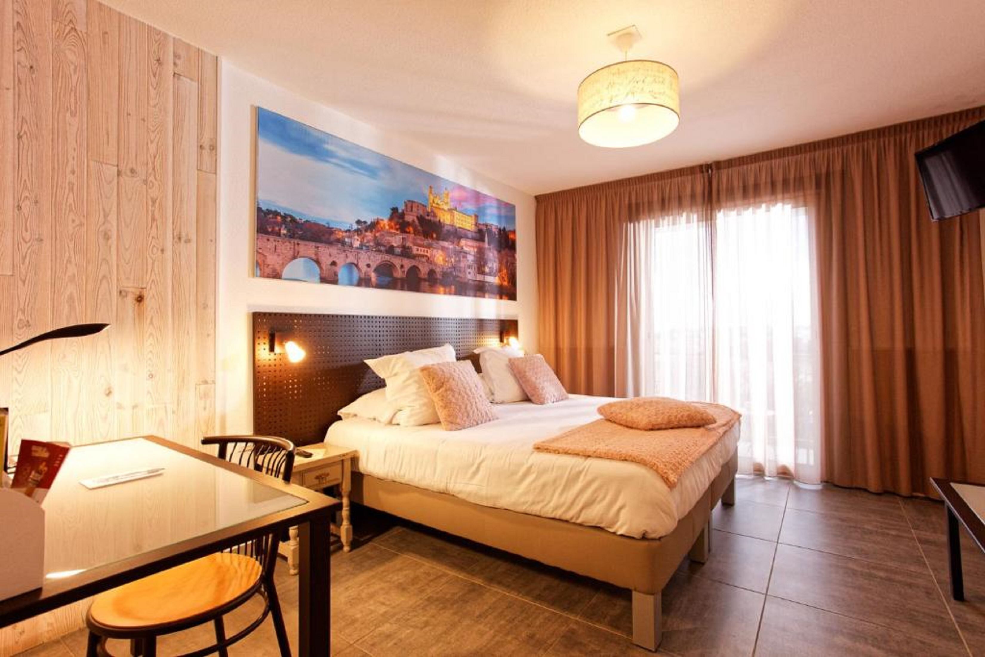 A hotel room with a bed, a desk, a chair, a television, and a large window with curtains.