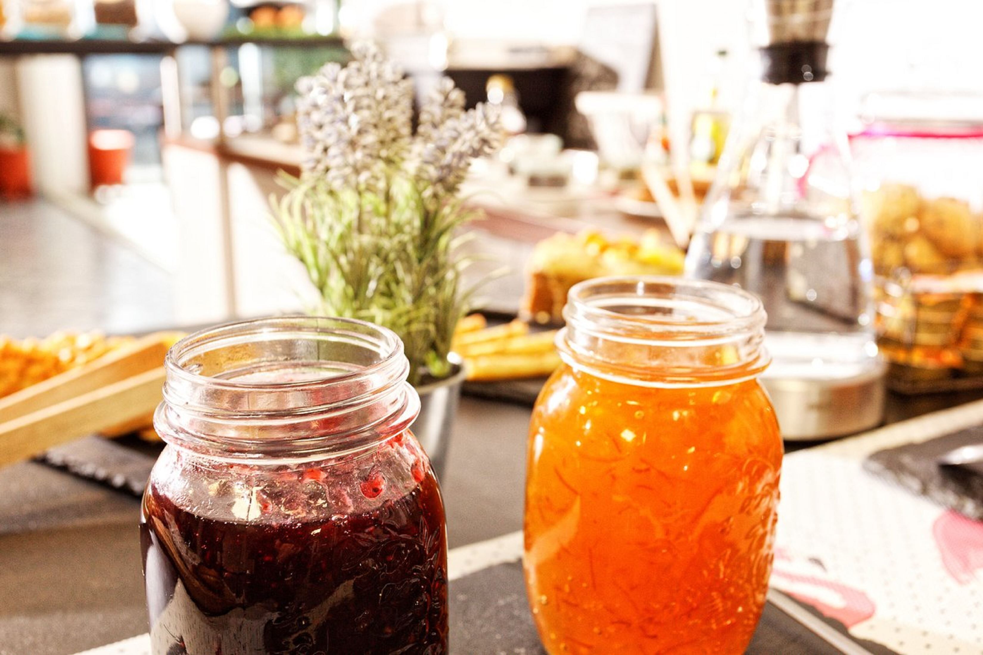 Two glass jars filled with food items, a potted plant, and a variety of food on a table.