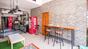 A bar area with a stone wall, a wooden door, and a Coca-Cola vending machine. - OYO 288 The Minotel Hotel (Patong)