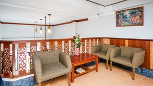 A room with a wooden bench, a small table, and a decorative vase. - OYO 288 The Minotel Hotel (Patong)