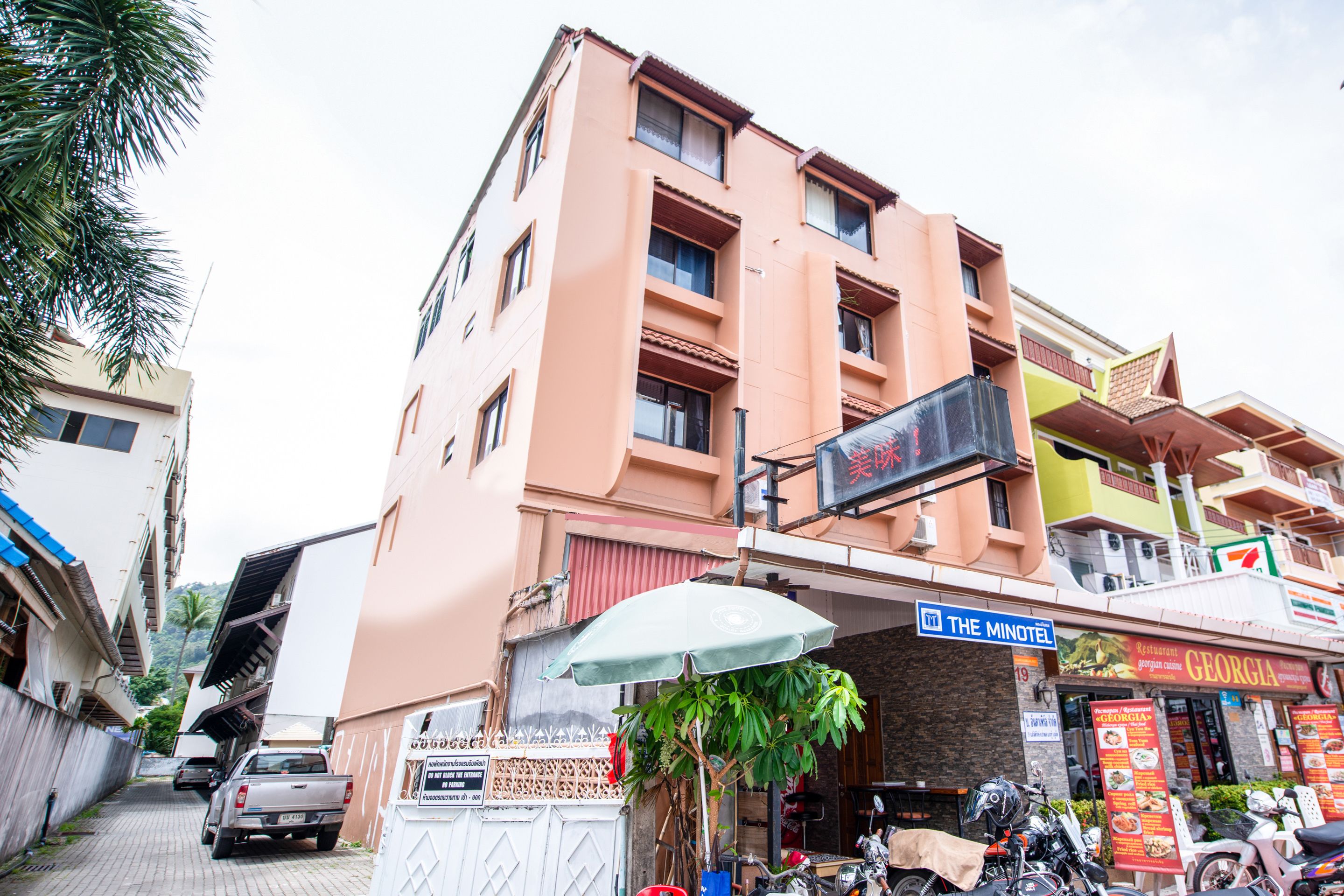 A multi-story building with a sign for 'The Minotel' and a 7-Eleven store.