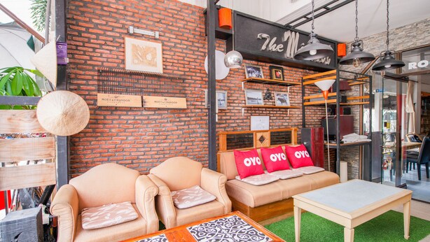 A cozy interior with brick walls, two beige sofas with red pillows, a patterned coffee table, and a small wooden table. - OYO 288 The Minotel Hotel (Patong)