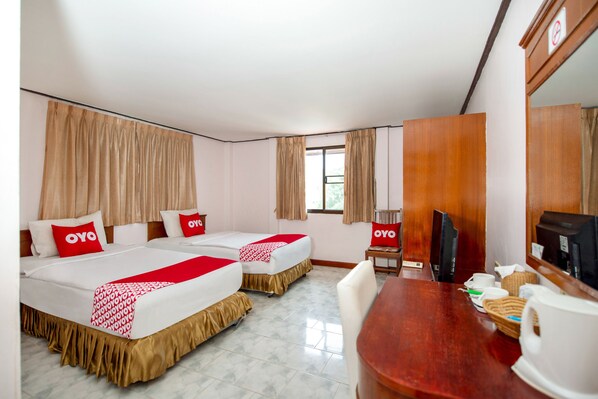 A hotel room with two beds, a wooden desk, a TV, and a window with curtains. - OYO 288 The Minotel Hotel (Patong)
