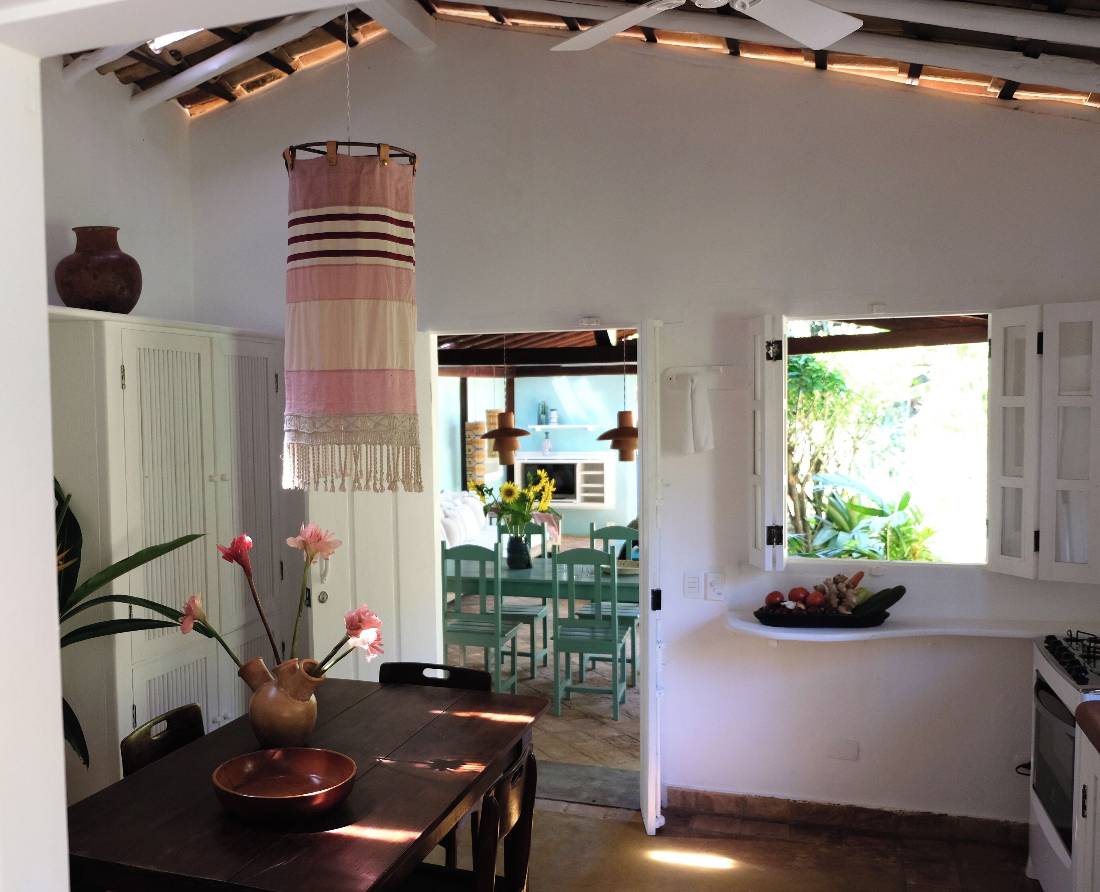 A kitchen with a dining area, a hanging light fixture, and a view of the outdoors.