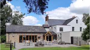 A building with a stone facade, large windows, and a wooden entrance. - The Queens (Carlisle)