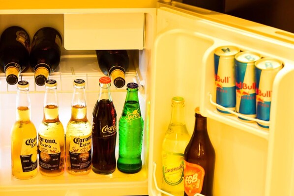 Een koelkast gevuld met diverse dranken, waaronder Corona Extra bier, Sprite, Coca-Cola en Red Bull energydrank.